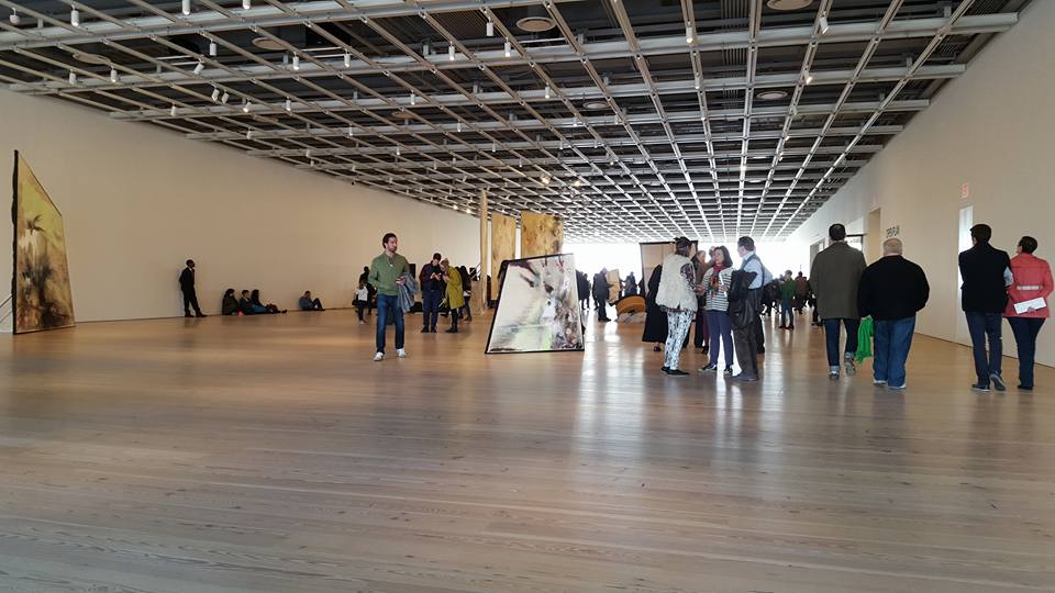 people standing at a museum setting with a wide wooden floor