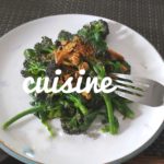 photo of cooked spinach leaves on a white plate and a fork with the word cuisine