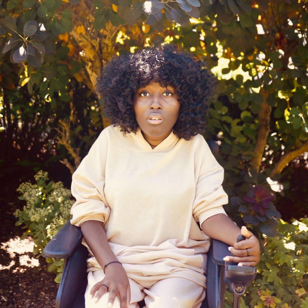 Young, Black woman in a wheelchair looking directly at the camera.