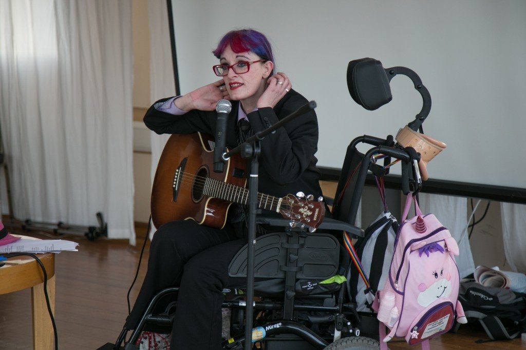 white person with glasses on wheelchair and with guitar