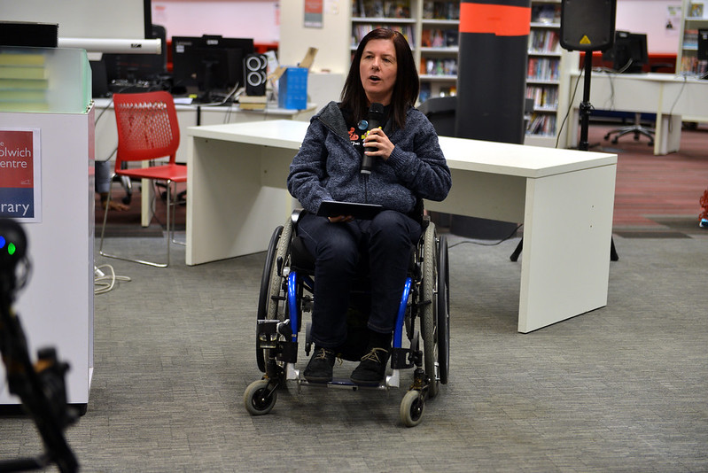 white woman, wheelchair user, with a microphone